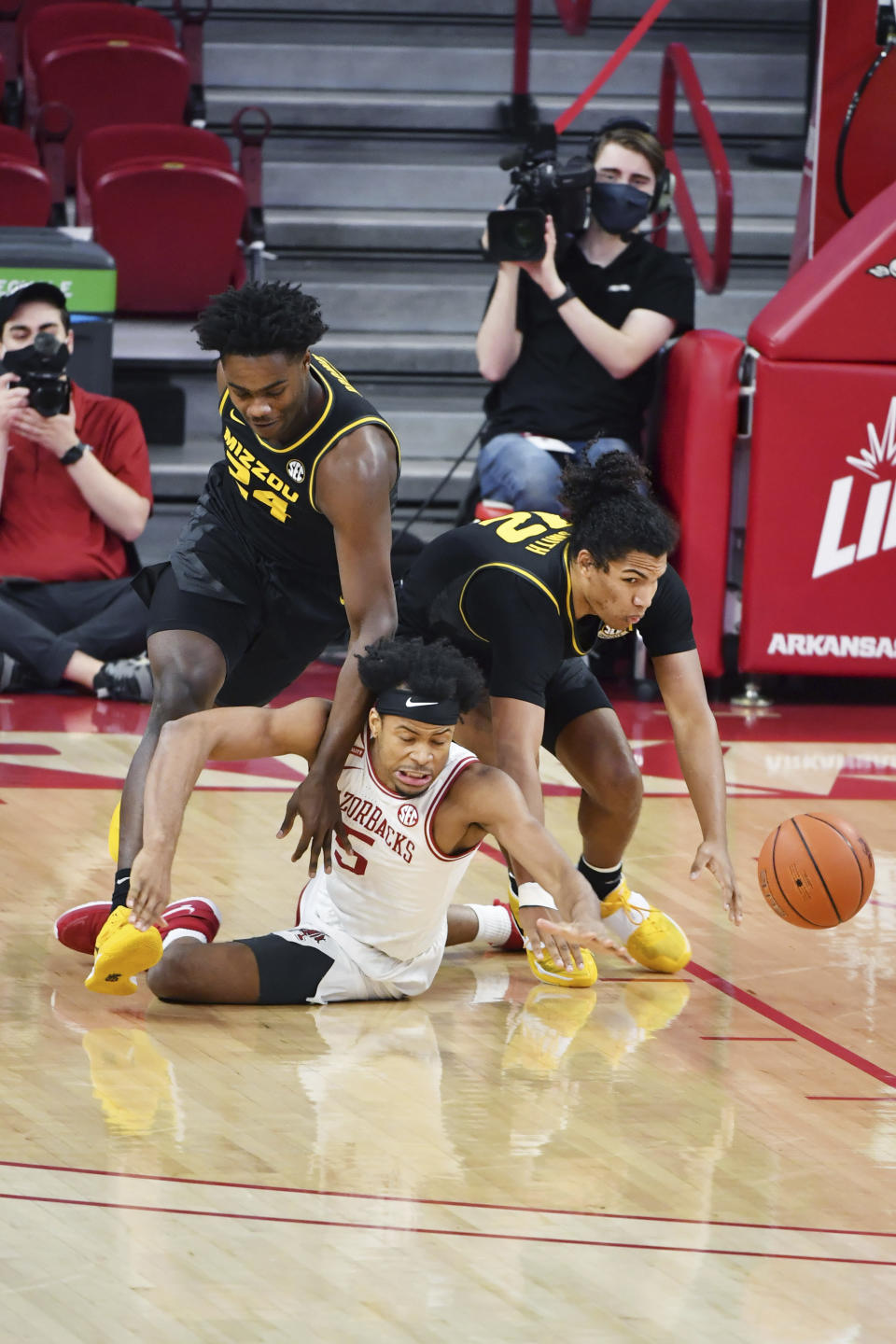 Arkansas forward Moses Moody (5) and Missouri's Kobe Brown (24) and Dru Smith (12) fight for a loose ball during the first half of an NCAA college basketball game in Fayetteville, Ark. Saturday, Jan. 2, 2021. (AP Photo/Michael Woods)