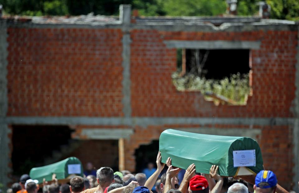 Bosnian Muslims carry coffins of their relatives during a mass funeral in front of a war-torn house in the village of Biscani, near Prijedor July 20, 2014. (REUTERS/Dado Ruvic)