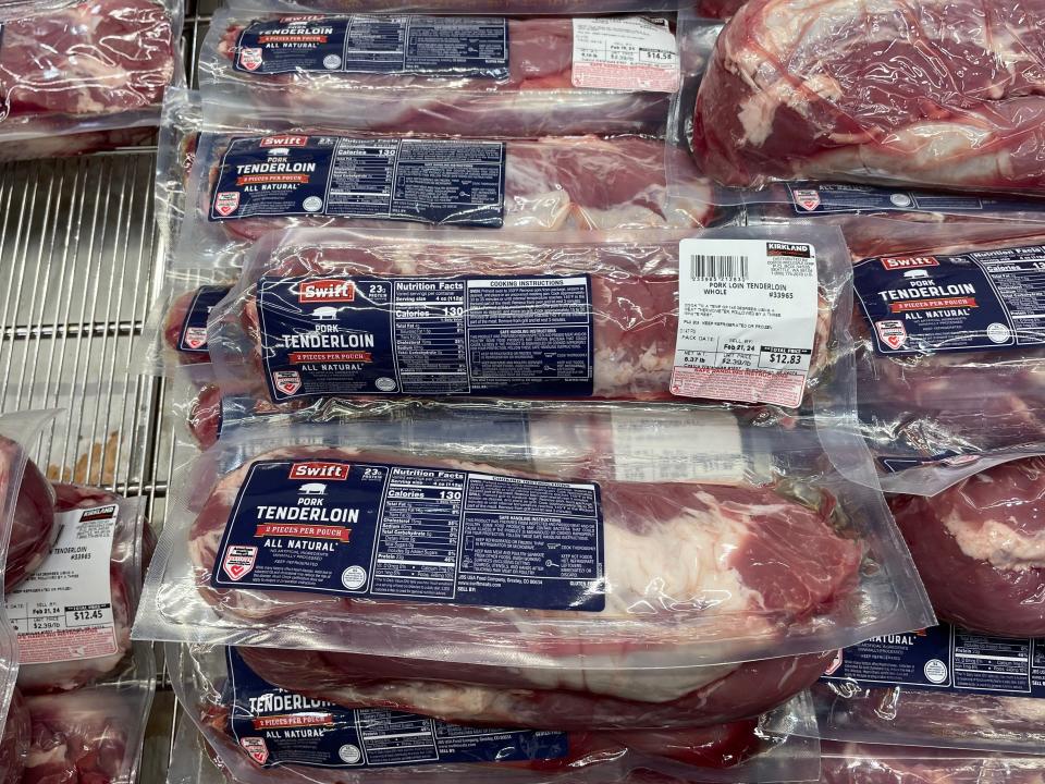 Vaccuum-sealed packages of pork tenderloin with blue labels in refrigerated section at Costco