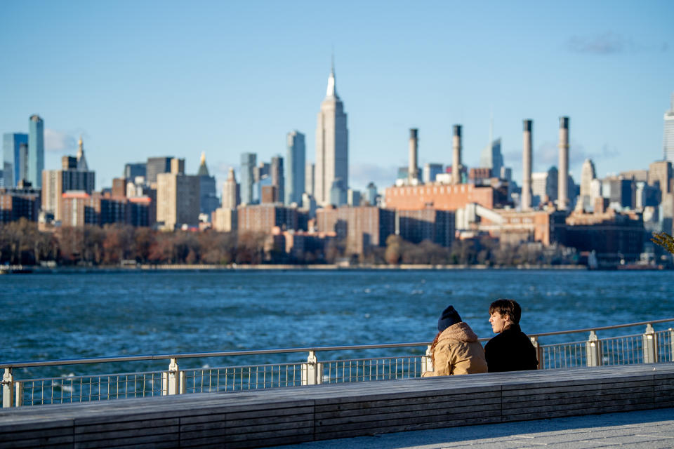 Visitors to Domino Park in Williamsburg, Brooklyn sit on the boardwalk with the Empire State Building in the background during the coronavirus pandemic on November 23, 2020 in New York City.