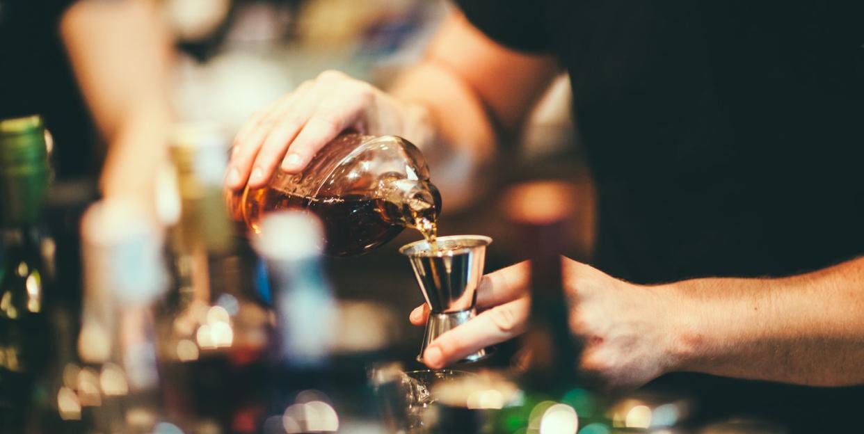 a few hands pouring liquid into a glass