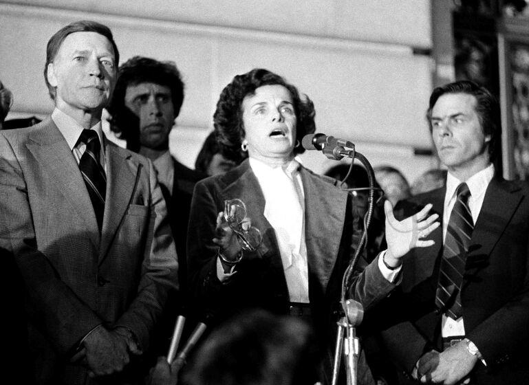 Acting Mayor Dianne Feinstein with Police Chief Charles Gain at left, addresses the more than 25,000 people jammed around San Francisco's City Hall, Nov. 28, 1978 as city residents staged a spontaneous memorial service for slain officials Mayor George Moscone and Supervisor Harvey Milk. Man at right is not identified. (AP Photo)