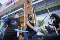 Volunteers clean up broken glass and damaged merchandise at The Pike Outlets on Monday, June 1, 2020, in Long Beach after overnight protests over the death of George Floyd . Floyd died in police custody on Memorial Day in Minneapolis. (AP Photo/Ashley Landis)