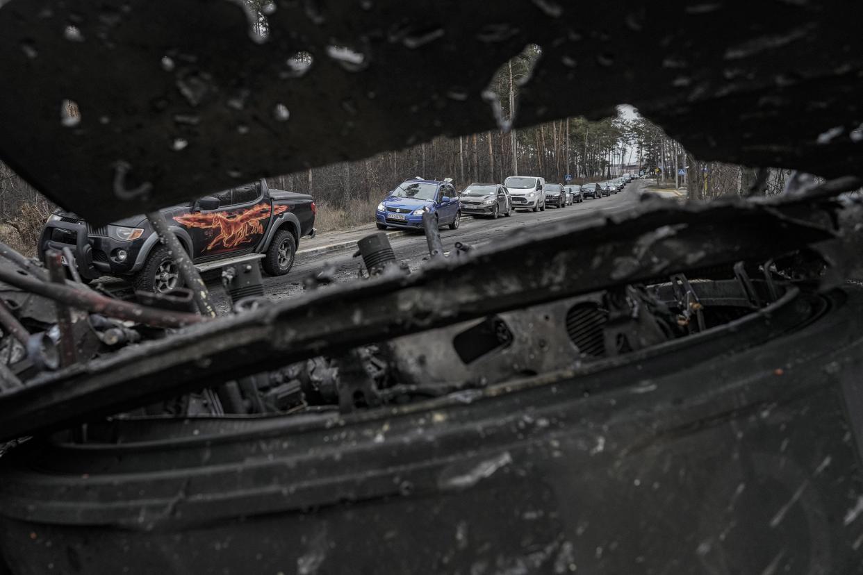 Cars drive past a destroyed Russian tank as a convoy of vehicles evacuating civilians leaves Irpin, on the outskirts of Kyiv, Ukraine, Wednesday, March 9, 2022.