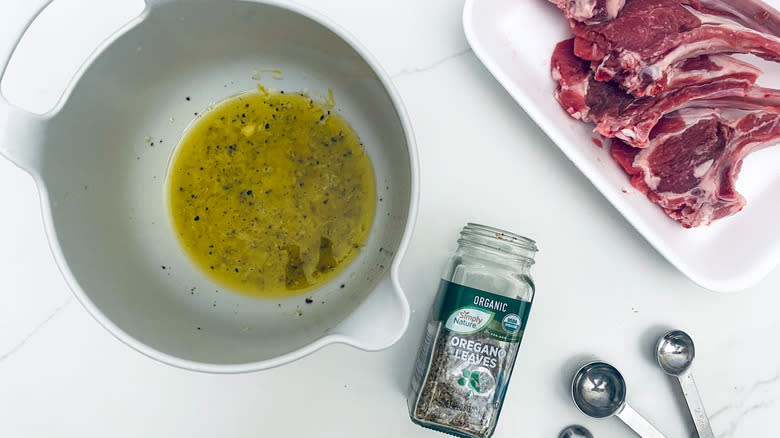 meat marinade in bowl next to oregano and raw meat