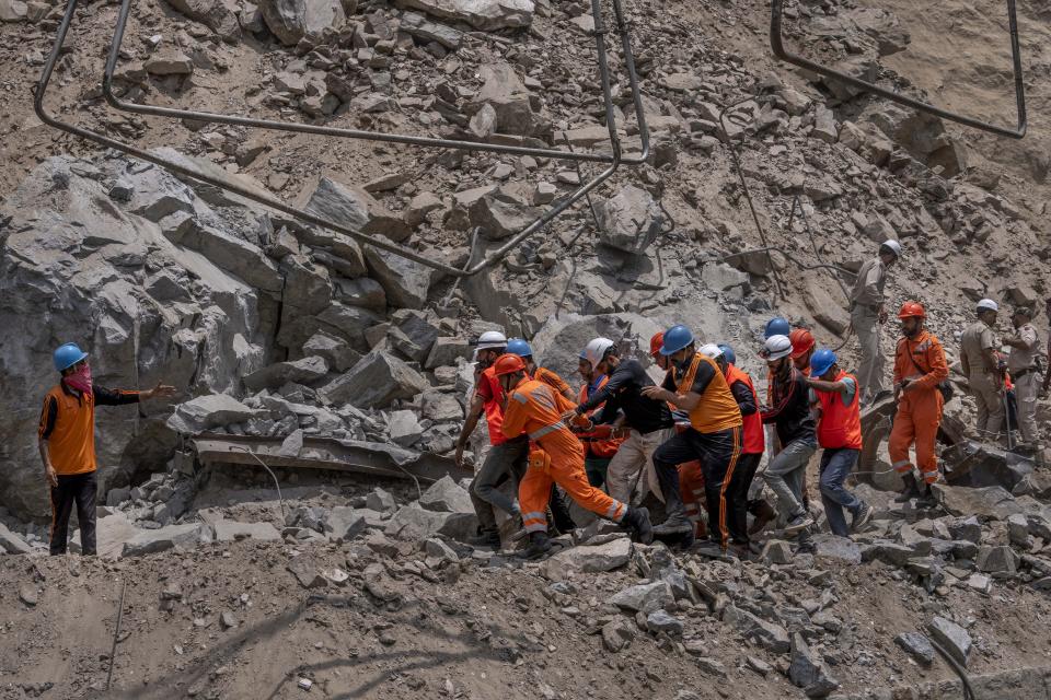 Rescue workers carry the body of a victim at the site of a collapsed tunnel in Ramban district, south of Srinagar, Indian controlled Kashmir, Friday, May 20, 2022. An official in Indian-controlled Kashmir said Friday that 10 workers were trapped after part of a road tunnel collapsed in the Himalayan region. (AP Photo/Dar Yasin)