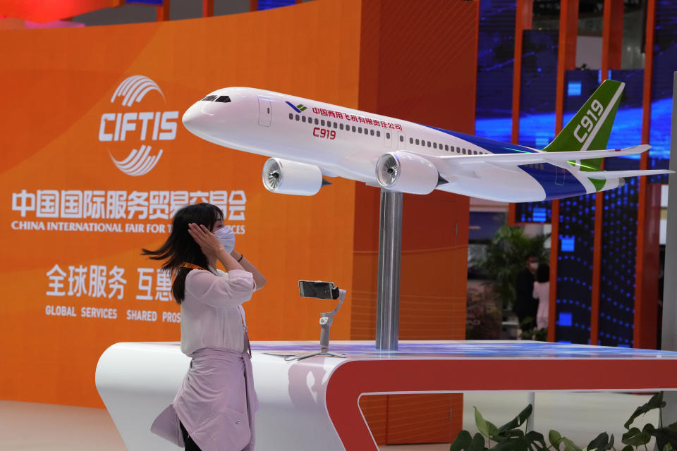 A woman adjusts her hair near a model of the Chinese made C919 passenger jet at a trade fair in Beijing on Sept. 1, 2022. A meeting of the ruling Communist Party to install leaders gives President Xi Jinping, China's most influential figure in decades, a chance to stack the ranks with allies who share his vision of intensifying pervasive control over entrepreneurs and technology development. (AP Photo/Ng Han Guan)