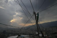 A man fixes power lines in the San Agustin neighborhood of Caracas, Venezuela, Sunday, May 17, 2020. President Nicolas Maduro is relaxing quarantine measures over the weekend by allowing children and older adults out of their homes for a few hours each day. (AP Photo/Matias Delacroix)