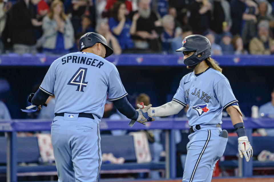 Toronto Blue Jays' Bo Bichette, right, and teammate George Springer (4) celebrate his two-run home run against the Houston Astros during the sixth inning of a baseball game in Toronto, Sunday, May 1, 2022. (Christopher Katsarov/The Canadian Press via AP)