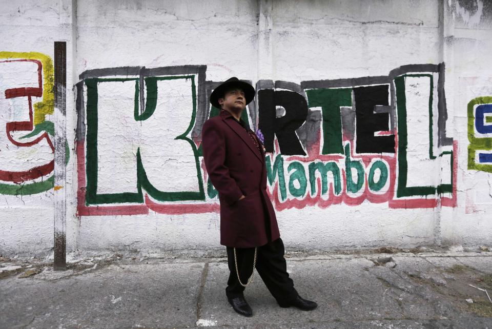 Arellano Diaz wears his "Pachuco" outfit while posing for a photograph next to a wall with graffiti in Mexico City