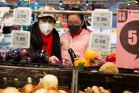 People wear face masks as they select products in a supermarket in Beijing