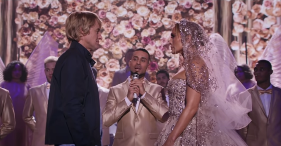 A plainly dressed man stands in front of a bride on stage