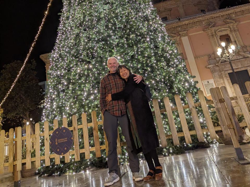 May Leong and her husband posing in front of an outdoor Christmas tree in Valencia.