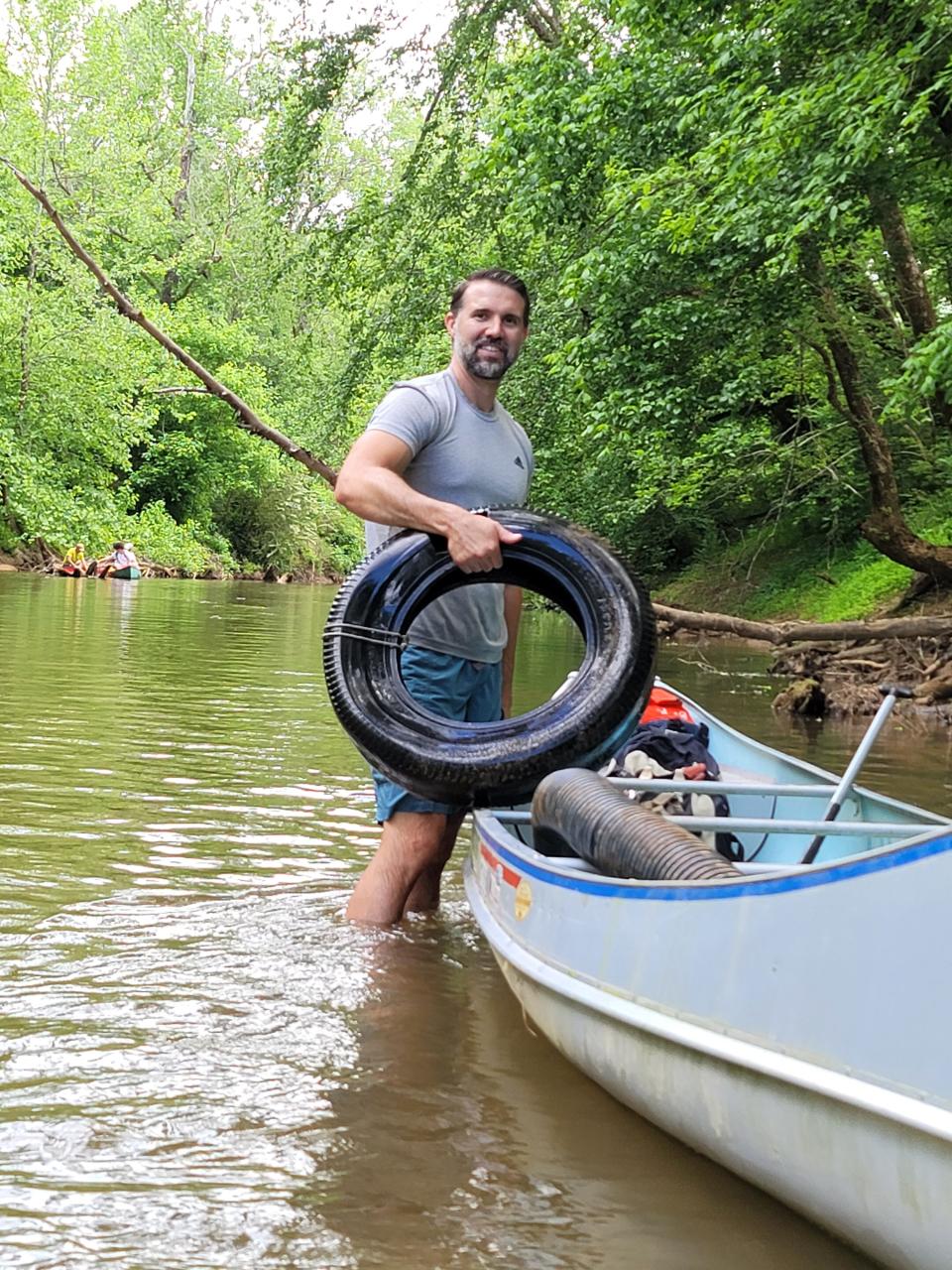 Justin Merritt pulls a tire from the water during the recent litter sweep.