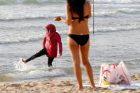 A Muslim woman wearing a Hijab kicks the water in the Mediterranean Sea as a woman wearing a bikini stands nearby at the beach in Tel Aviv, Israel August 30, 2016. REUTERS/Baz Ratner