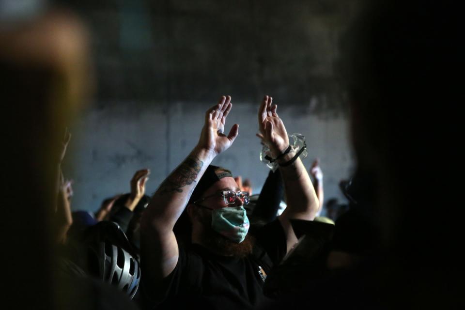 Demonstrators in downtown L.A. hold their hands up as police gather during a protest over the shooting of Jacob Blake.