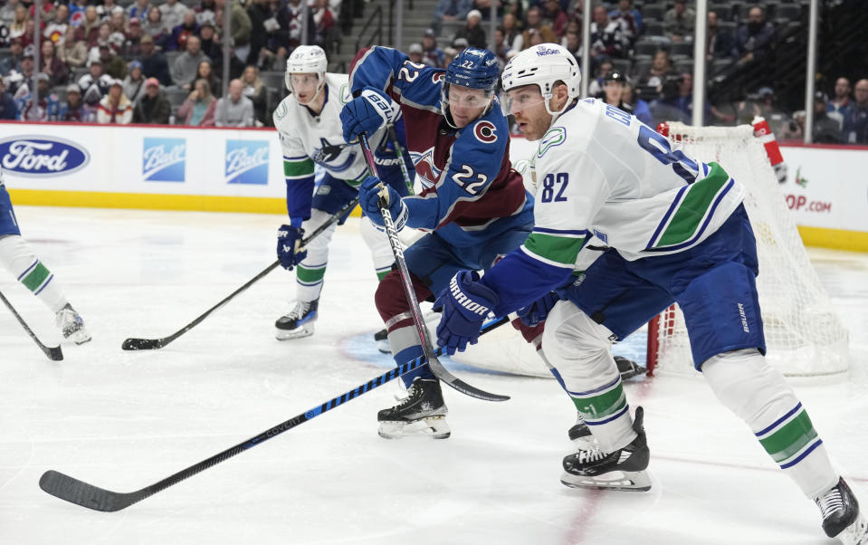 Vancouver Canucks defenseman Ian Cole, front, works for the puck against Colorado Avalanche center Fredrik Olofsson during the third period of an NHL hockey game Wednesday, Nov. 22, 2023, in Denver. (AP Photo/David Zalubowski)