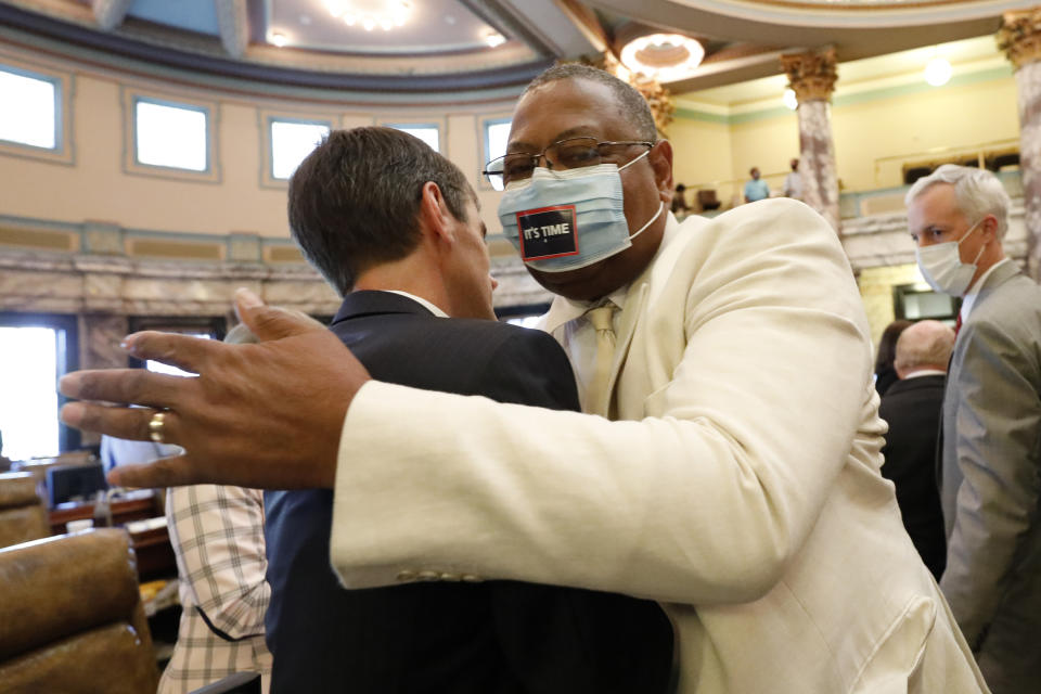 Sen. Briggs Hopson, left, R-Vicksburg, is hugged by Sen. Robert Jackson, D-Marks, after the Senate voted to change the state flag, Sunday, June 28, 2020, at the Capitol in Jackson, Miss. Hopson presented the bill to the body. Lawmakers in both chambers voted to surrender the Confederate battle emblem from their state flag. Republican Gov. Tate Reeves has said he will sign the bill. (AP Photo/Rogelio V. Solis)