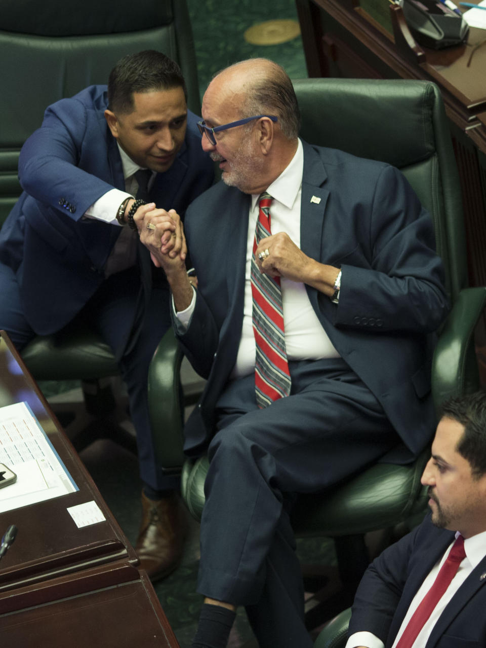 Luis "Junior" Perez, center, shakes hands with fellow lawmakers Urayoan Hernandez as members of Puerto Rico's House of Representatives celebrate their vote to confirm Pedro Pierluisi as secretary of state, in San Juan, Puerto Rico, Friday, Aug. 2, 2019. The confirmation removes an important obstacle to him becoming governor. But Pierluisi's fate remains unclear. (AP Photo/Dennis M. Rivera Pichardo)