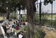 A stray dog sleeps on a sidewalk as former diplomat Virendra Gupta, far right, and his singer wife Veena Gupta teach underprivileged children in New Delhi, India, on, Sept. 3, 2020. The Indian couple are conducting free classes for underprivileged children on a sidewalk in New Delhi with the goal to keep them learning and not left behind when schools reopen. As most schools in India remain shut since late March when the country imposed a nationwide lockdown to curb the spread of COVID-19, many switched to digital learning and taking classes online. (AP Photo/Manish Swarup)