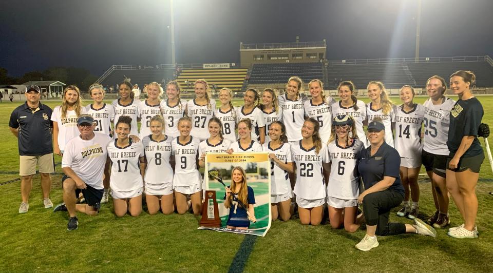 The Gulf Breeze girls lacrosse team celebrates with its trophy after claiming the District 1-2A championship game over Niceville on Tuesday, April 16, 2024.