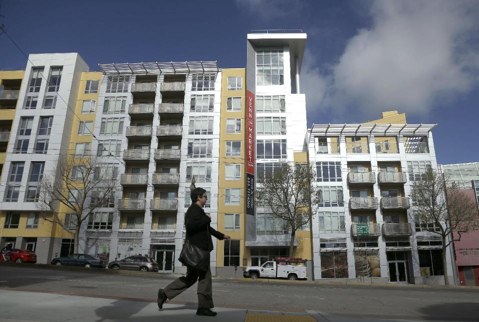 In this Monday, March 17, 2014, photo, a woman walks across the street from the Venn on Market apartment and condominium building in San Francisco. Entering the 2014 spring buying season, the U.S. housing market faces an unusual dilemma: Too few people are selling homes. Yet too few buyers can afford the homes that are for sale. A 13.4 percent jump in the average price of a home sold last year, according to the Standard & Poor's/Case-Shiller 20-city index, hasn’t managed to coax more homeowners to sell. And combined with higher mortgage rates, higher prices have made homes costlier for first-time buyers as well as for all-cash investors. (AP Photo/Jeff Chiu)