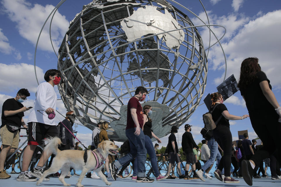 Protesters march a round large sculpture of a globe in Flushing Meadows Corona Park in the Queens borough of New York, Sunday, May 31, 2020. Demonstrators took to the streets of New York City to protest the death of George Floyd, a black man who was killed in police custody in Minneapolis on May 25. (AP Photo/Seth Wenig)