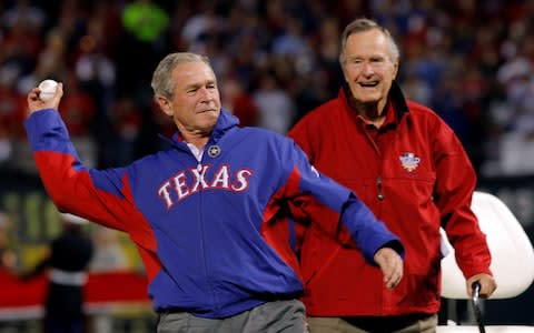 Former U.S. President George H.W. Bush (R) watches as his son, former President George W. Bush, throws a ceremonial first pitch in Arlington - Credit: Reuters