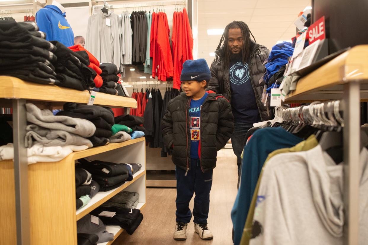 Javon Timley, first-grader at Ross Elementary, browses a selection of hoodies and sweaters at Kohl's with the help from Advisors Excel employee Devin Seats on Wednesday. Thanks to a partnership between Topeka Public Schools and Advisors Excel, about 120 students were given the opportunity to help their family shop for gifts.