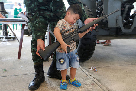 A Thai army soldier gives a weapon to a boy to pose for a picture during Children's Day celebration at a military facility in Bangkok, Thailand January 14, 2017. REUTERS/Jorge Silva