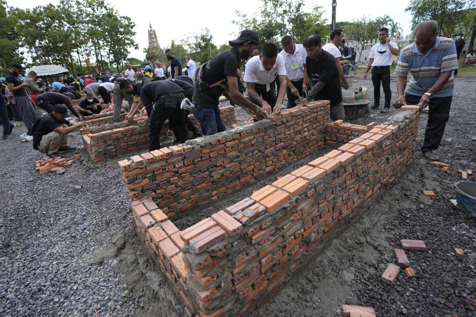 Locals lay bricks for cremation furnaces at Wat Rat Samakee temple in Uthai Sawan, northeastern Thailand, Monday, Oct. 10, 2022. The furnaces were being built Monday to cremate the bodies of the mostly young victims of last week’s massacre at a day care center by a former policeman. (AP Photo/Sakchai Lalit)