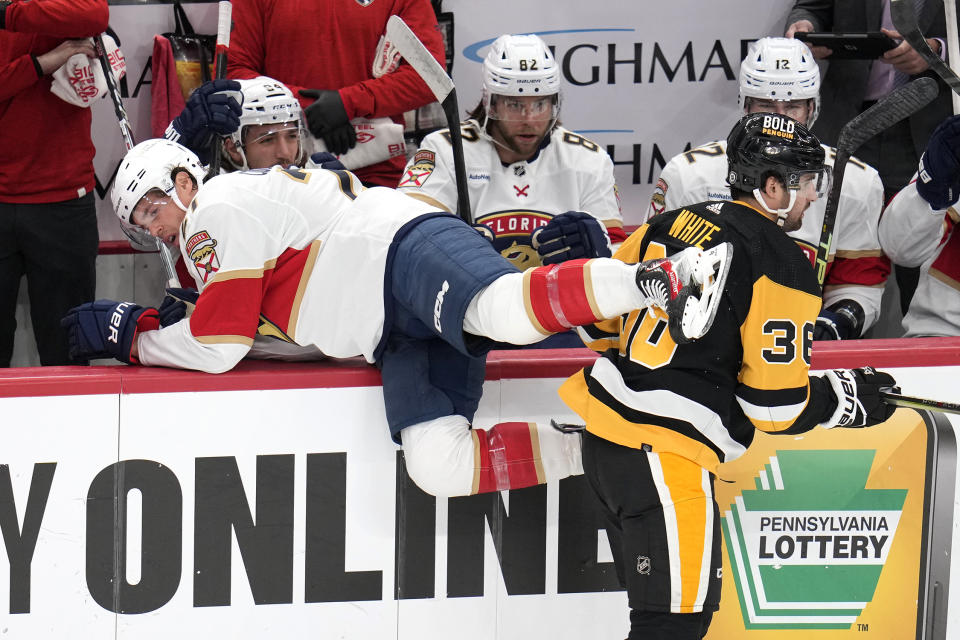 Florida Panthers' Nick Cousins, left, is checked into his bench by Pittsburgh Penguins' Colin White (36) during the first period of an NHL hockey game in Pittsburgh, Wednesday, Feb. 14, 2024. (AP Photo/Gene J. Puskar)