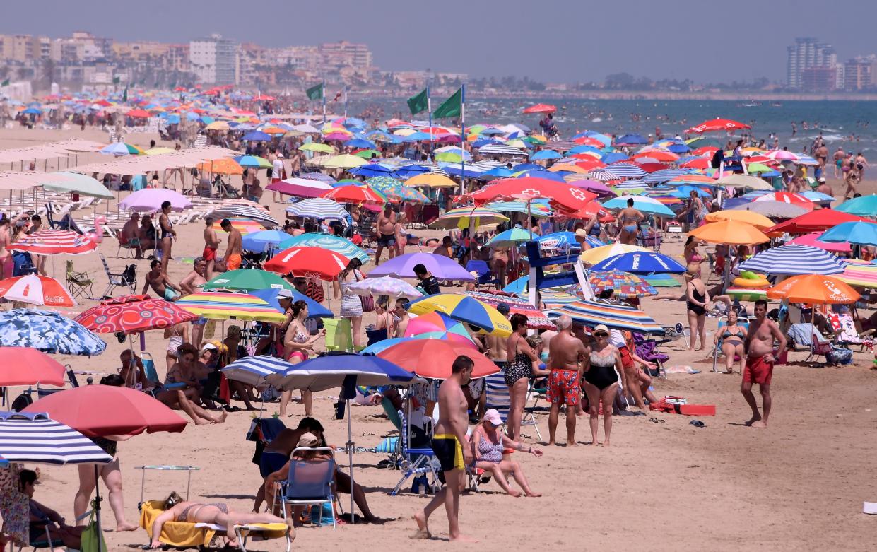 People enjoy a day at the Nord Beach in Gandia, Spain, near Valencia, on July 1, 2020. The European Union reopened its borders to visitors from 15 countries, but excluded the United States, where coronavirus deaths are spiking once again.