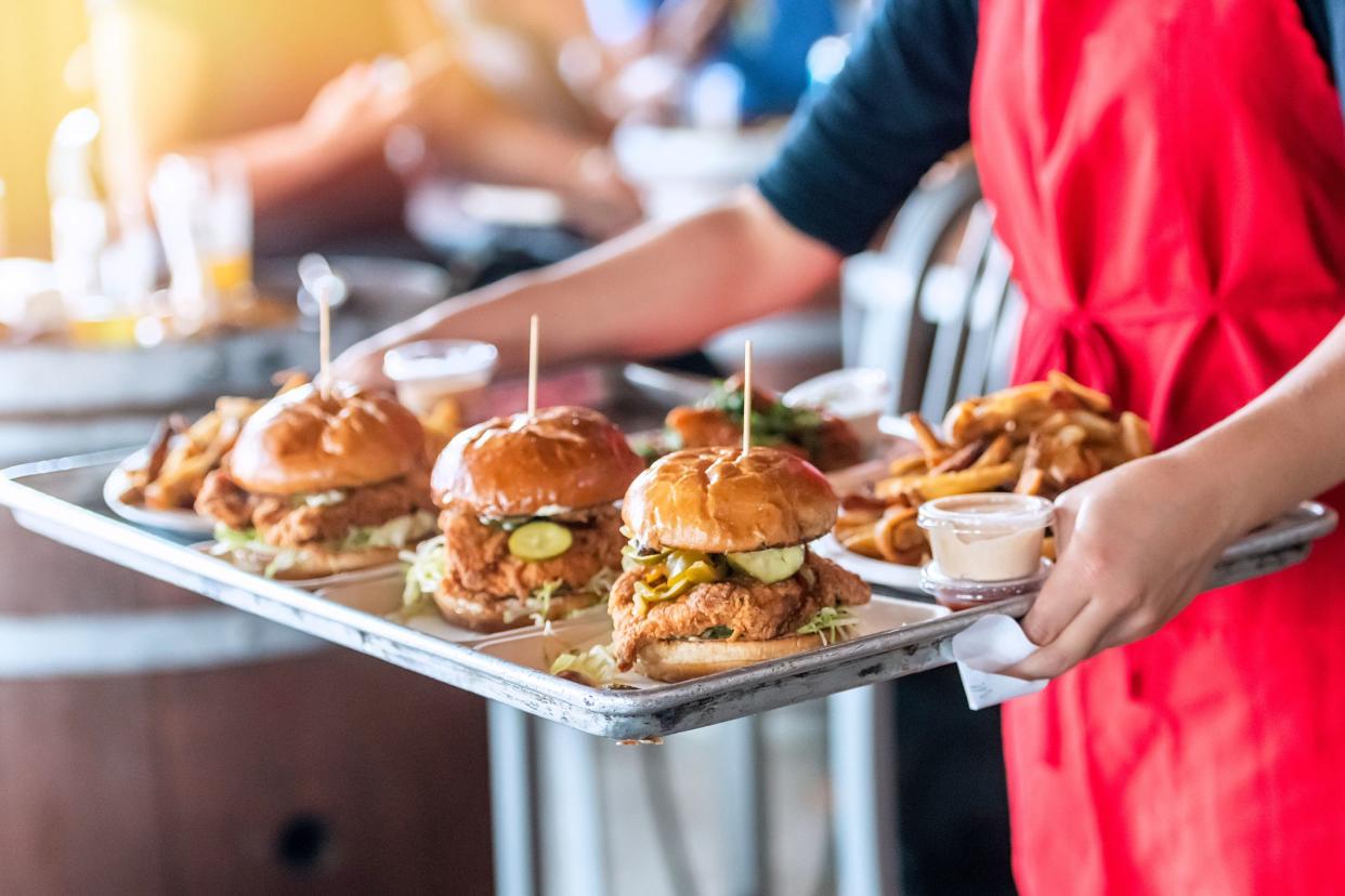 Waitress carrying a tray of fried chicken sandwiches and French fries