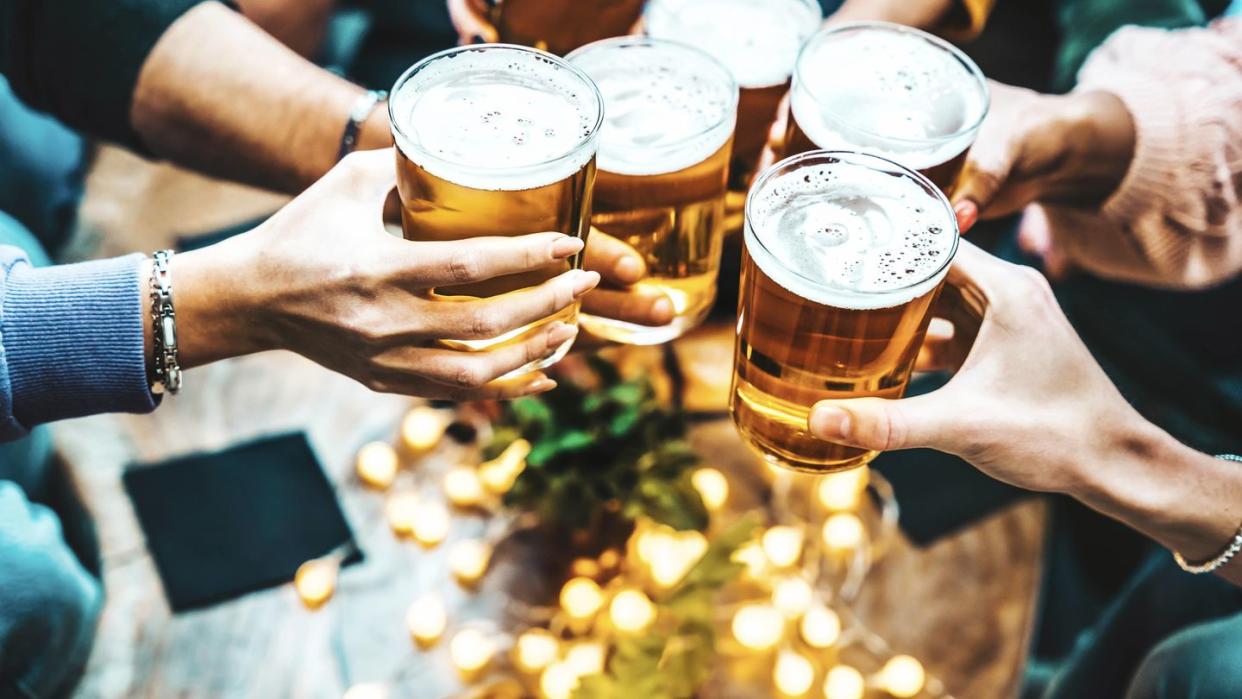 group of people drinking beer at brewery pub restaurant happy friends enjoying happy hour sitting at bar table closeup image of brew glasses food and beverage lifestyle concept