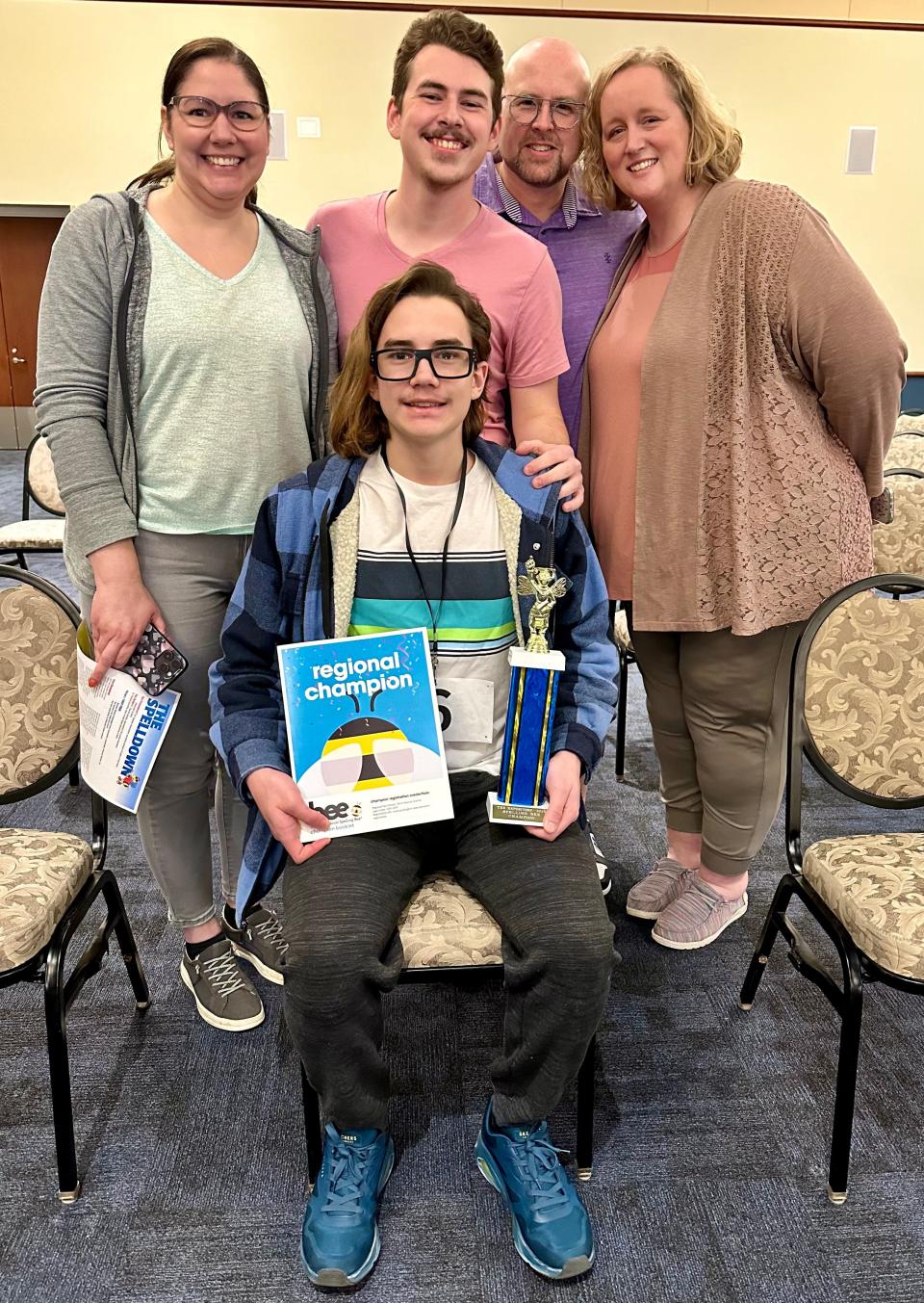 Logan Cox, seated, is surrounded by his family after winning The Canton Repository Regional Final Spelling Bee on Saturday, March 16, 2024, at Kent State University at Stark's Conference Center. Standing from left are Logan's mom Dawn Cox, brother Dawson Cox, dad Jeff Cox and stepmom Melanie Cox.