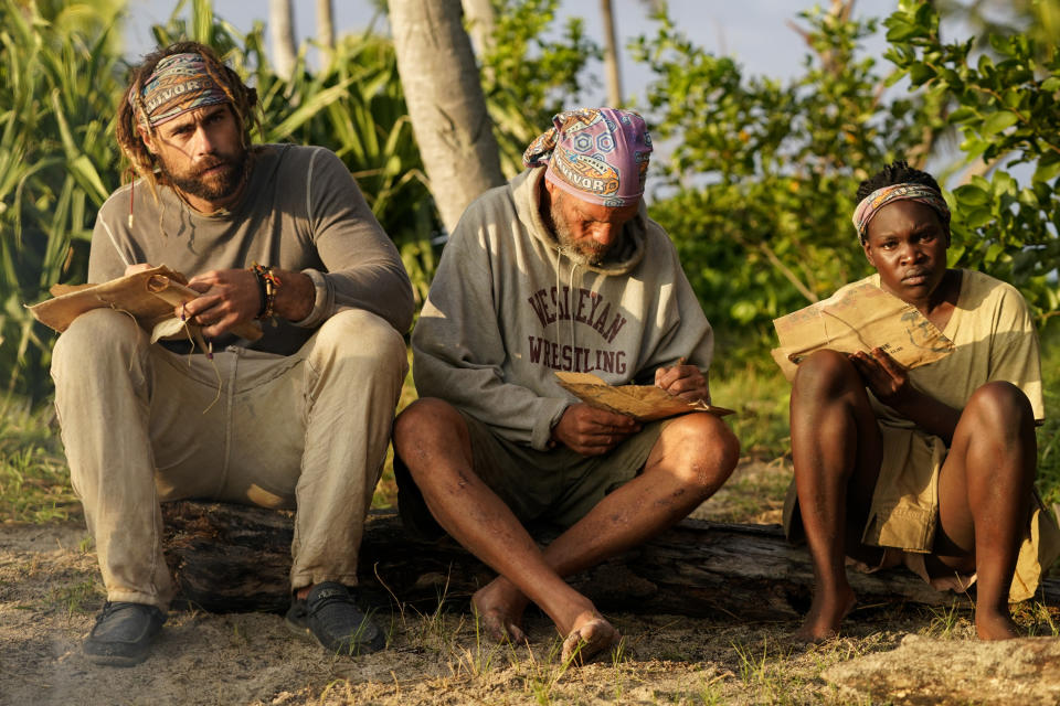 three people sitting on a log of wood outside