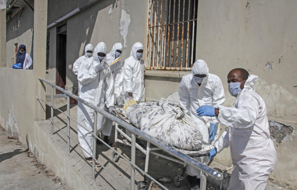 Medical workers in protective suits remove the body of a patient who died from COVID-19 from a ward for coronavirus patients at the Martini hospital in Mogadishu, Somalia Wednesday, Feb. 24, 2021. (AP Photo/Farah Abdi Warsameh)