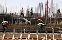 Workers wearing protective face masks stand on a building under construction in the New Administrative Capital (NAC), east of Cairo