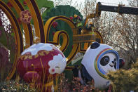 Workers wearing face masks to help protect from the coronavirus set up a decoration for the Winter Olympic Games in Beijing, Sunday, Jan. 16, 2022. Beijing has reported its first local omicron infection, according to state media, weeks before the Winter Olympic Games are due to start. (AP Photo/Andy Wong)