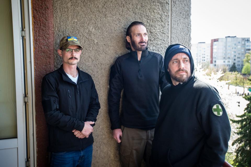 Erik Inbody, former U.S. Marine Corps infantryman (L), Matthew VanDyke, head of the non-profit Sons of Liberty International (SOLI) (C) and former U.S. Army combat medic Jason (R) on the balcony of a hotel room in Lviv, Ukraine, on May 1, 2022.