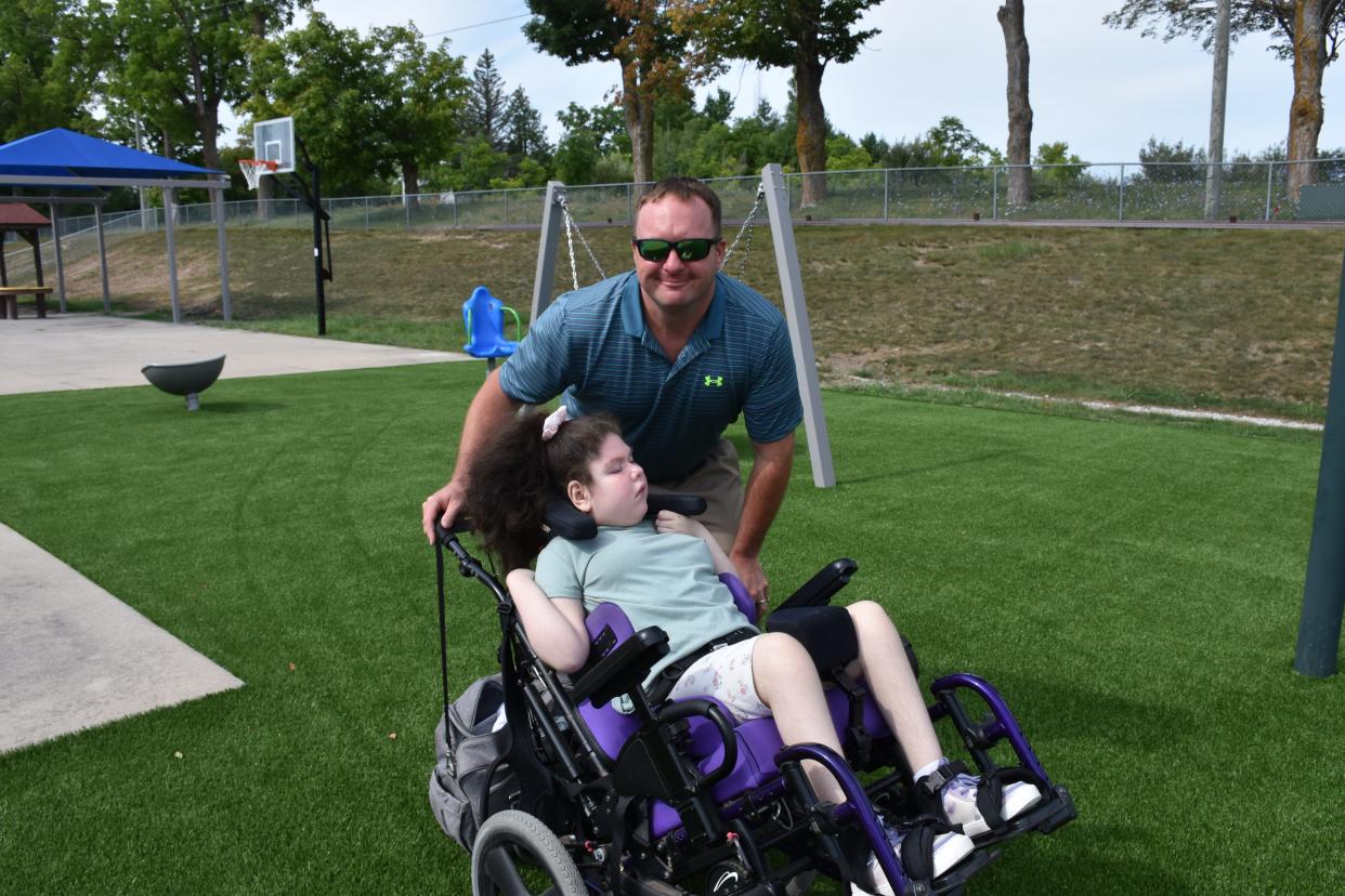 Char-Em ISD special education teacher Mike Olivier takes a student for a tour of the newly redesigned and improved-access playground at Taylor School in summer 2023.