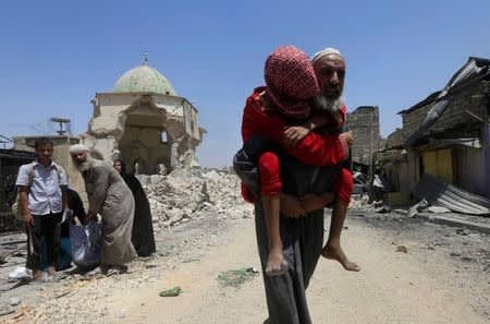 A displaced Iraqi man who fled from clashes carries a child in the Old City of Mosul, Iraq July 1, 2017. REUTERS/Alaa Al-Marjani