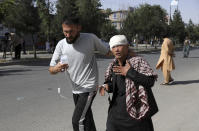 An Afghan man helps an injured man after a bomb explosion in Kabul, Afghanistan, Saturday, June 12, 2021. Separate bombs hit two minivans in a mostly Shiite neighborhood in the Afghan capital Saturday, killing several people and wounding others, the Interior Ministry said. (AP Photo/Rahmat Gul)