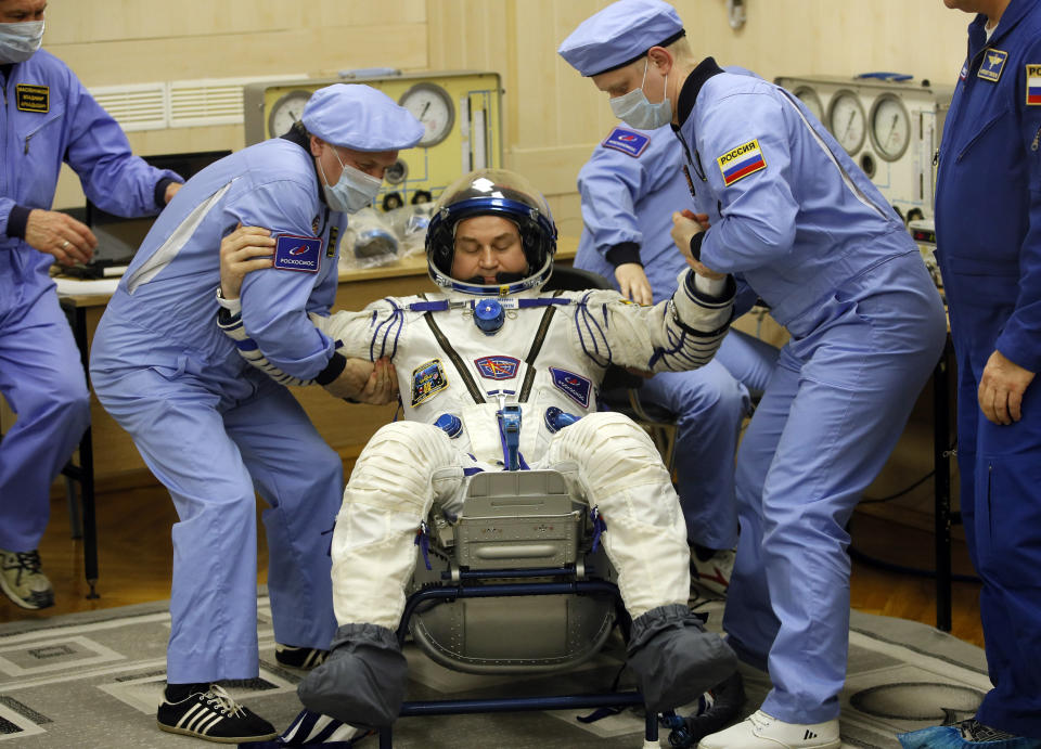 Russian Space Agency experts help Russian cosmonaut Alexey Ovchinin, member of the main crew of the expedition to the International Space Station (ISS), to stand up after inspecting his space suit prior the launch of Soyuz MS-12 space ship at the Russian leased Baikonur cosmodrome, Kazakhstan, Thursday, March 14, 2019. (AP Photo/Dmitri Lovetsky)