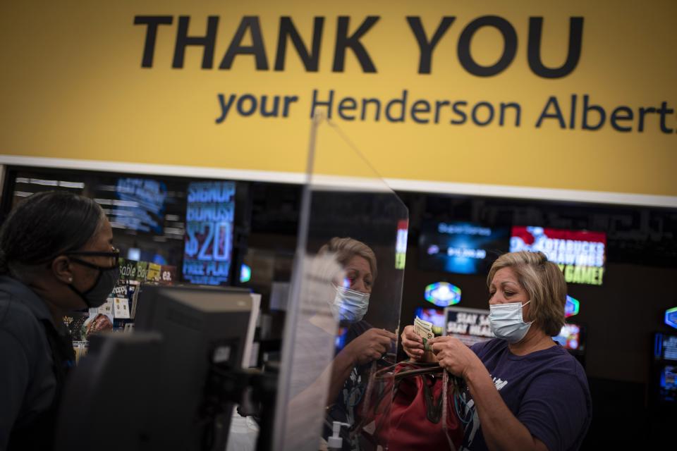 Norma Flores, 54, pays for her groceries at a store near her home in Henderson, Nev., Tuesday, Nov. 10, 2020. Flores is a Mexican immigrant who spent two decades working as a waitress at the Fiesta before COVID-19 descended and she lost her job. At night, she often lies awake, worrying about paying the rent, buying gas, getting enough food. Like millions of other people across the U.S., her unemployment benefits run out the day after Christmas. She's terrified her family could end up homeless. (AP Photo/Wong Maye-E)