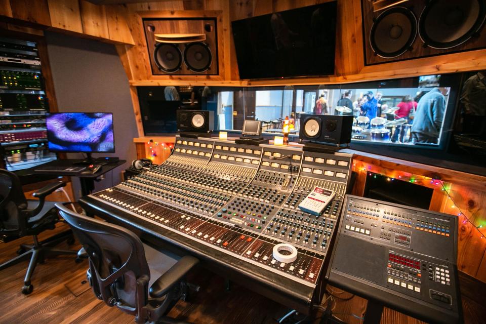 People touring through The Church Studio view a recording studio sound board console.