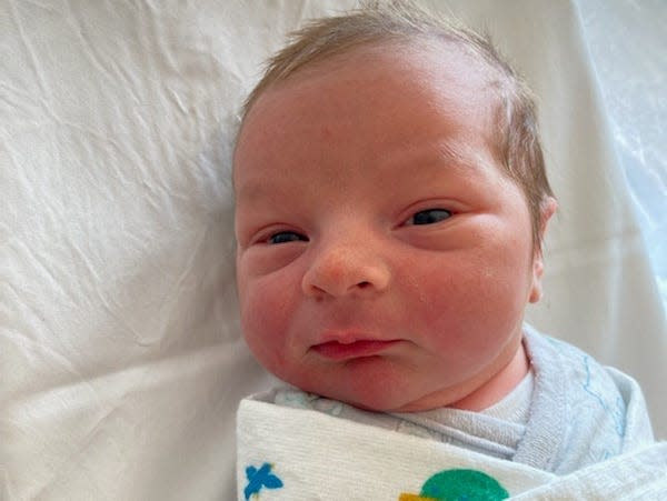 picture of ronan with eyes open, one day old, swaddled in hospital crib