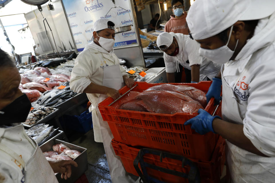 Workers load an order of red snapper for a client onto a cart at the La Nueva Viga seafood market, part of the Central de Abastos, the capital's main market amid the COVID-19 pandemic, in Mexico City, Wednesday, Dec. 9, 2020. With numbers of reported COVID-19 infections on the rise, shoppers and sellers worry how increased restrictions will affect their businesses during this year’s holiday season. (AP Photo/Rebecca Blackwell)
