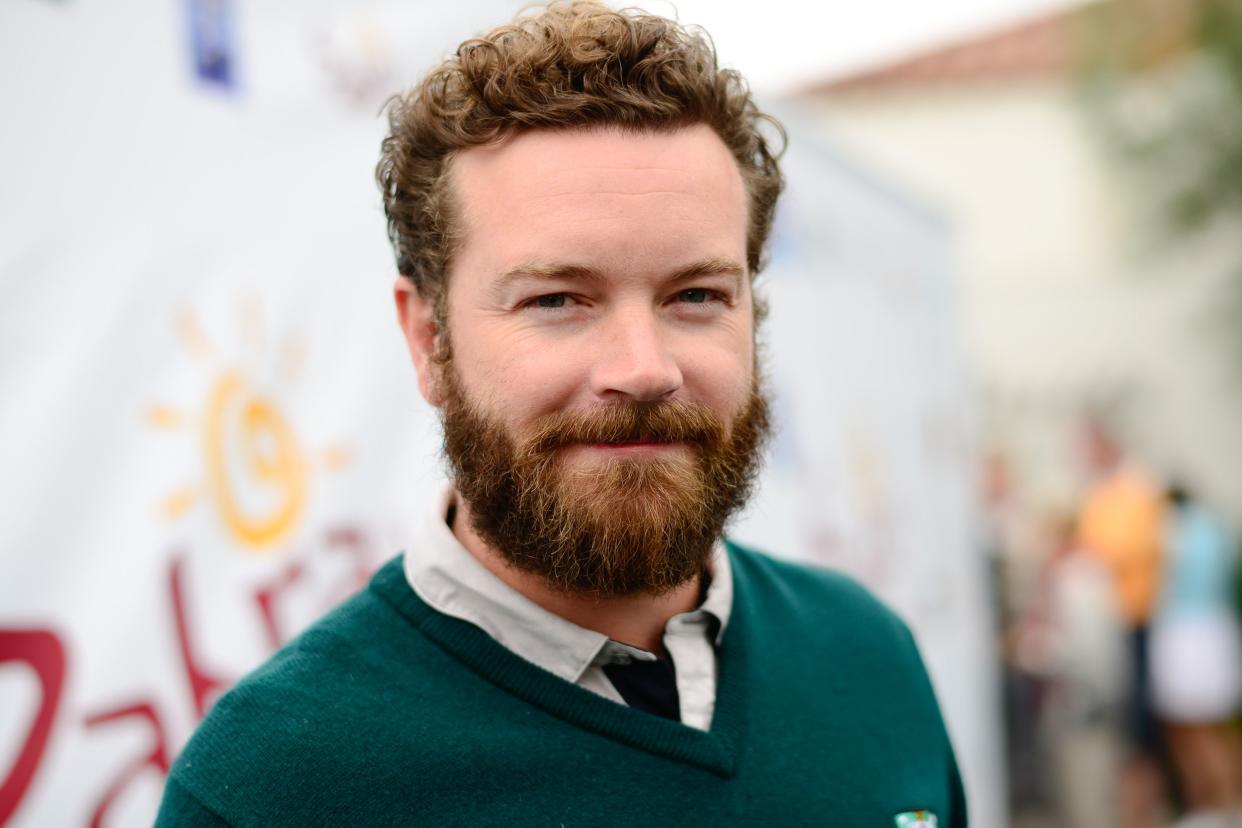 Danny Masterson headshot, smiling, wearing a green dress sweater and tie.